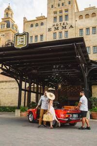 un grupo de personas de pie delante de un coche rojo en Hotel Emma at Pearl on the Riverwalk, en San Antonio