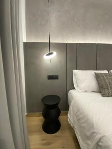 un dormitorio con una cama con un taburete negro al lado en Tramonto Maisonettes & Suites, en Parga