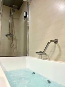 a bath tub with a shower with blue water at Turia Granada in Granada