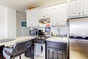 a kitchen with white cabinets and a stove and a chair at Harbour Beach Resort Unit 518 in Daytona Beach