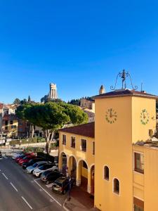 un edificio amarillo con una torre de reloj junto a un aparcamiento en Hôtel Napoléon, en La Turbie