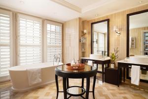 a bathroom with a tub and a table and two sinks at Corinthia London in London