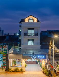 un bâtiment blanc avec un panneau devant lui dans l'établissement Nhý Villa Đà Lạt Review, à Đà Lạt