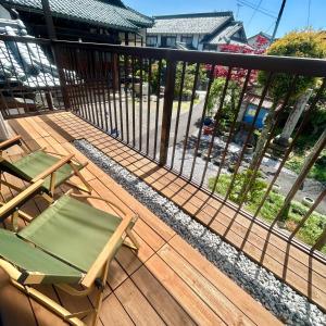 einen Balkon mit zwei Stühlen und einem Zaun in der Unterkunft 湖北 寺の宿-去-来-現Ko-Rai-Gen in Nagahama