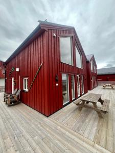 - un bâtiment rouge avec une table de pique-nique sur une terrasse dans l'établissement Finnvika Lodges, à Stamsund