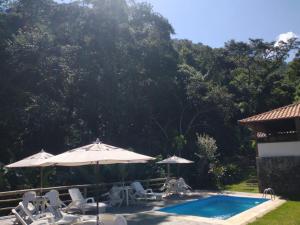 una piscina con sillas y sombrillas junto a en Pousada dos Anjos, en São Pedro da Serra