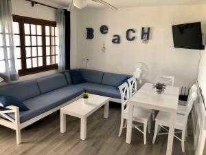 uma sala de estar com um sofá azul e uma mesa em Apartamento el Descanso em Son Bou