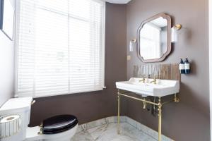 a bathroom with a sink and a toilet and a mirror at The King in Fowey