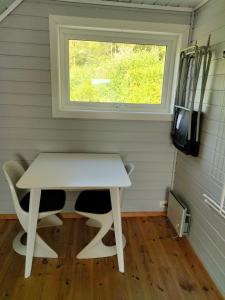 a small white table in a room with a window at Anneks i naturskjønne Gitlevåg in Lyngdal