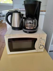 a microwave with a coffee pot on top of it at Anneks i naturskjønne Gitlevåg in Lyngdal