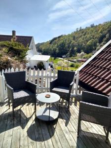 a deck with chairs and a table and a fence at Anneks i naturskjønne Gitlevåg in Lyngdal