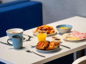 a table with plates of breakfast foods and orange juice at Ibis Budget Strasbourg Centre Gare in Strasbourg