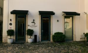 a white building with green doors and potted plants at Memmo Alfama - Design Hotels in Lisbon