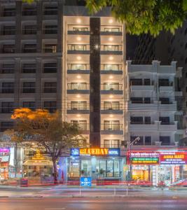 Un grand bâtiment blanc avec des panneaux de néon devant lui dans l'établissement Bluebay Hotel, à Nha Trang