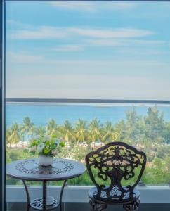 une table et deux chaises devant une fenêtre dans l'établissement Bluebay Hotel, à Nha Trang