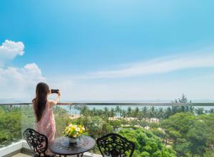 une femme prenant une photo de la vue depuis son balcon dans l'établissement Bluebay Hotel, à Nha Trang