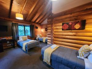 a bedroom with two beds in a log cabin at Rainforest Retreat in Franz Josef