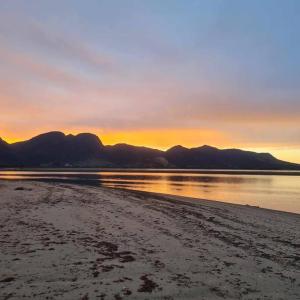 - un coucher de soleil sur une plage avec des montagnes en arrière-plan dans l'établissement Beachfront escape, à Collingwood