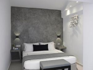 a bedroom with a large bed with a gray wall at Kalisti Hotel & Suites in Fira