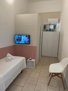 Camera piccola con letto, sedia e TV. di GARIBALDI ROOMS a Reggio di Calabria