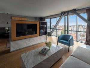 a living room with a large tv and a blue chair at Sofitel Istanbul Taksim in Istanbul