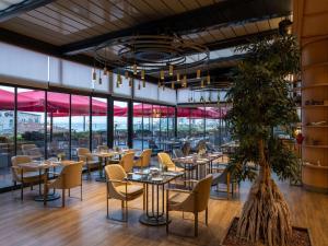 a restaurant with tables and chairs and a plant at Sofitel Istanbul Taksim in Istanbul