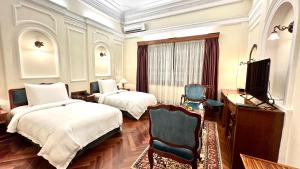 a bedroom with two beds and a desk and a television at Hotel Majestic Saigon in Ho Chi Minh City