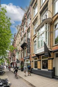 people riding bikes down a city street with buildings at Hotel Atlantis Amsterdam in Amsterdam