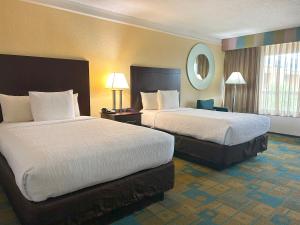 a hotel room with two beds and a mirror at Hotel SonoHotel By Monreale IDrive in Orlando