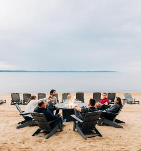 eine Gruppe von Menschen, die am Strand am Tisch sitzen in der Unterkunft Alexandra Inn in Traverse City