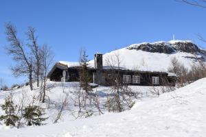 a house in the snow with a mountain in the background at Skeikampen Booking in Svingvoll