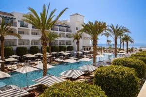 METT Hotel & Beach Resort Marbella Estepona في إِستيبونا: منتجع فيه مسبح فيه مظلات والنخيل