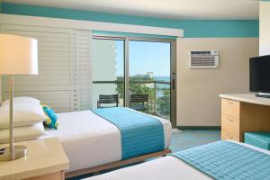 a hotel room with two beds and a balcony at Aston Waikiki Circle Hotel in Honolulu