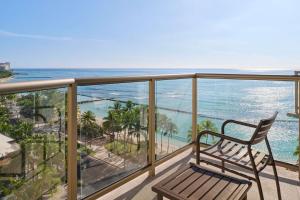 a balcony with a chair and a view of the ocean at Aston Waikiki Circle Hotel in Honolulu