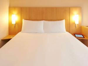 uma grande cama branca num quarto de hotel em ibis Strasbourg Centre Historique em Estrasburgo