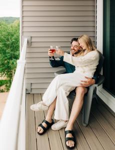 eine Braut und ein Bräutigam sitzen auf einer Veranda mit Gläsern Wein in der Unterkunft Alexandra Inn in Traverse City