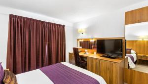 a hotel room with a bed and a flat screen tv at Magnuson Hotel Sandy Lodge Newquay in Newquay