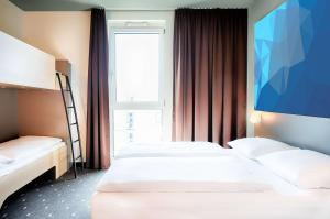 a hotel room with two beds and a large window at B&B HOTEL Offenburg-Hbf in Offenburg