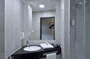 a bathroom with a sink and a shower and a mirror at B&B HOTEL Offenburg-Hbf in Offenburg