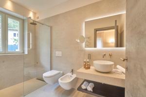 a bathroom with a sink and a toilet and a mirror at Hotel Villa Cuserina in Cannobio