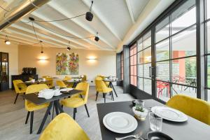 a restaurant with tables and yellow chairs and windows at Hotel Villa Cuserina in Cannobio