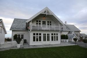 une maison blanche avec une véranda et une clôture blanche dans l'établissement Alnes Gård, à Ålesund