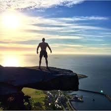 Un homme debout sur un rocher dans l'eau dans l'établissement Alnes Gård, à Ålesund