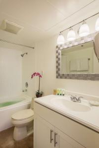 a bathroom with a sink and a toilet and a mirror at Aston at the Executive Centre Hotel in Honolulu