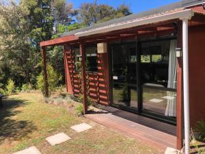 a small cabin with a wooden deck at Kanuka Ridge Lodge in Marahau