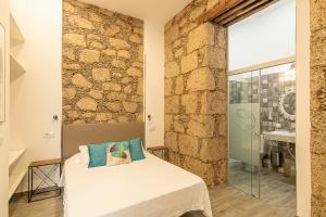 a bedroom with a bed and a stone wall at Hotel The Cathedral Vegueta in Las Palmas de Gran Canaria