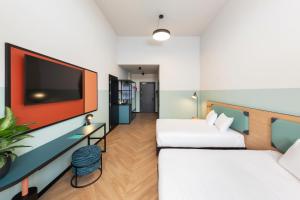 a hotel room with two beds and a flat screen tv at CX Milan Bicocca in Milan