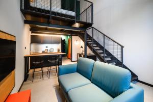 a living room with a blue couch and a staircase at CX Milan Bicocca in Milan