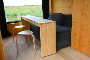 una mesa y dos taburetes junto a un sofá en Tiny House Nature 14 Zur Meerseite - Green Tiny Village Harlesiel, en Carolinensiel