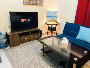 un salon avec un canapé bleu et une télévision dans l'établissement Premium Furnished studio, à Charjah